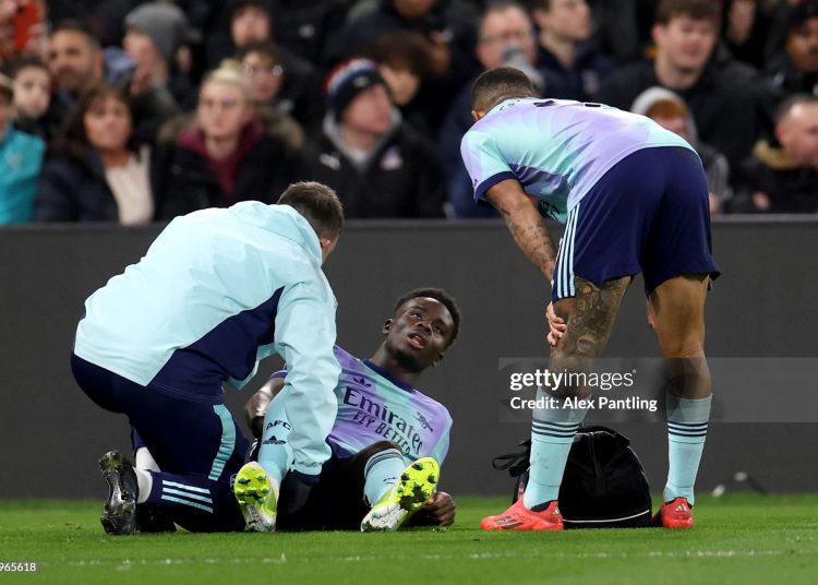 Bukayo Saka of Arsenal reacts as he receives medical treatment after picking up an injury whilst speaking with Gabriel Jesus (Photo by Alex Pantling/Getty Images)