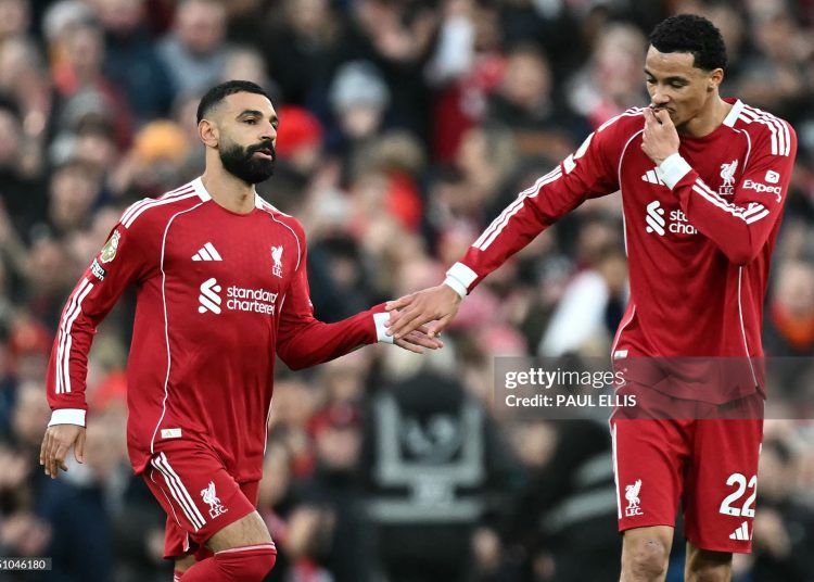 Liverpool's French striker #22 Hugo Ekitike (R) taps hands with Liverpool's Egyptian striker #11 Mohamed Salah as he comes off of the bench to play during the English Premier League football match between Liverpool and Brighton and Hove Albion (Photo by Paul ELLIS / AFP via Getty Images)