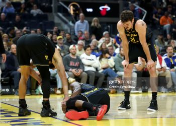 Jimmy Butler III #10 of the Golden State Warriors is looked at by Stephen Curry #30 and Quinten Post #21 after he collided with Davion Mitchell #45 of the Miami Heat and injured his knee during the third quarter (Photo by Ezra Shaw/Getty Images)