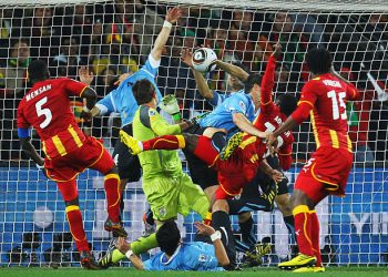 Dominic Adiyiah of Ghana heads the ball towards goal and Luis Suarez of Uruguay handles the ball off the line during the 2010 FIFA World Cup South Africa Quarter Final match between Uruguay and Ghana at the Soccer City stadium on July 2, 2010 in Johannesburg, South Africa.  (Photo by Paul Gilham - FIFA/FIFA via Getty Images)