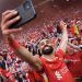 Mohamed Salah of Liverpool takes a selfie with the fans, as they celebrate the teams victory and confirmation of winning the Premier League title after the Premier League match between Liverpool FC and Tottenham Hotspur FC at Anfield on April 27, 2025 in Liverpool, England. (Photo by Carl Recine/Getty Images)