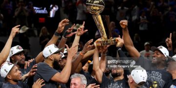 Jalen Brunson #11 of the New York Knicks lifts the Larry O'Brien Championship Trophy after the victory against the San Antonio Spurs in Game Five of the 2026 NBA Finals (Photo by Gregory Shamus/Getty Images)