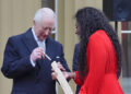 Britain's King Charles III places his message into the Commonwealth baton which is held by Kadeena Cox during the launch of the Commonwealth Sport King's Baton Relay, officially starting the countdown towards the Glasgow 2026 Commonwealth Games, at Buckingham Palace in London on March 10, 2025. (Photo by Jonathan Brady / POOL / AFP) (Photo by JONATHAN BRADY/POOL/AFP via Getty Images)
