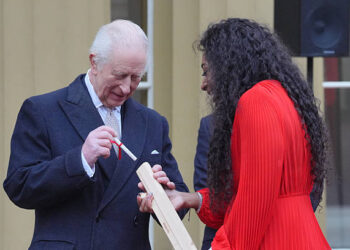 Britain's King Charles III places his message into the Commonwealth baton which is held by Kadeena Cox during the launch of the Commonwealth Sport King's Baton Relay, officially starting the countdown towards the Glasgow 2026 Commonwealth Games, at Buckingham Palace in London on March 10, 2025. (Photo by Jonathan Brady / POOL / AFP) (Photo by JONATHAN BRADY/POOL/AFP via Getty Images)