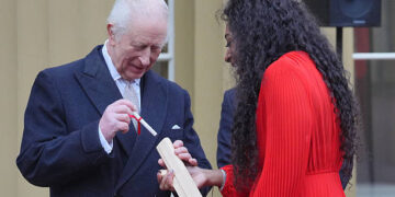 Britain's King Charles III places his message into the Commonwealth baton which is held by Kadeena Cox during the launch of the Commonwealth Sport King's Baton Relay, officially starting the countdown towards the Glasgow 2026 Commonwealth Games, at Buckingham Palace in London on March 10, 2025. (Photo by Jonathan Brady / POOL / AFP) (Photo by JONATHAN BRADY/POOL/AFP via Getty Images)