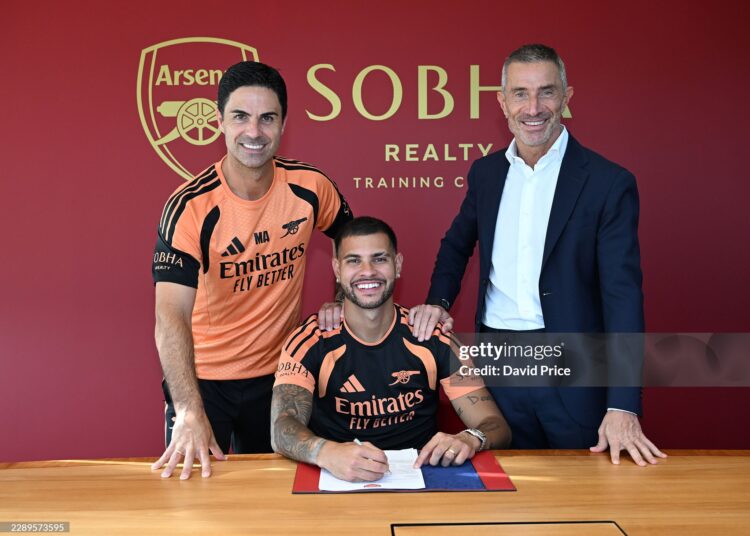Bruno Guimaraes signs for Arsenal alongside Manager Mikel Arteta and Arsenal Sporting Director Andrea Berta (Photo by David Price/Arsenal FC via Getty Images)